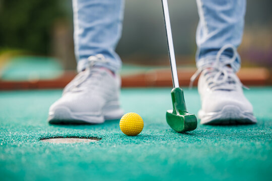 Golfer playing adventure or mini golf and trying putting ball into hole
