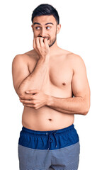 Fototapeta premium Young handsome man wearing swimwear looking stressed and nervous with hands on mouth biting nails. anxiety problem.