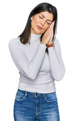 Beautiful brunette woman wearing casual clothes sleeping tired dreaming and posing with hands together while smiling with closed eyes.