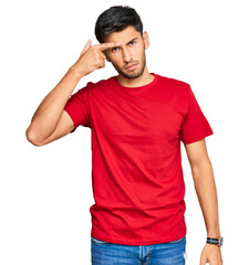 Young handsome man wearing casual red tshirt pointing unhappy to pimple on forehead, ugly infection of blackhead. acne and skin problem