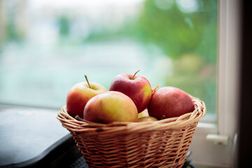 Fresh harvest of apples. Nature theme with red grapes and basket on windowsill background. Nature fruit concept..