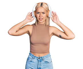 Beautiful young blonde woman listening to music using headphones clueless and confused expression. doubt concept.