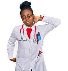 Young african american woman wearing doctor uniform and stethoscope suffering of neck ache injury, touching neck with hand, muscular pain