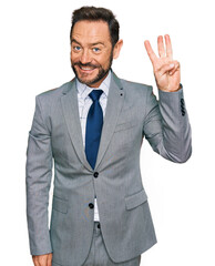 Middle age man wearing business clothes showing and pointing up with fingers number three while smiling confident and happy.