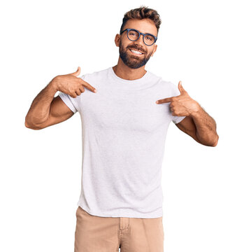 Young hispanic man wearing casual clothes and glasses looking confident with smile on face, pointing oneself with fingers proud and happy.