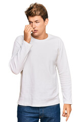 Handsome caucasian man wearing casual white sweater looking stressed and nervous with hands on mouth biting nails. anxiety problem.