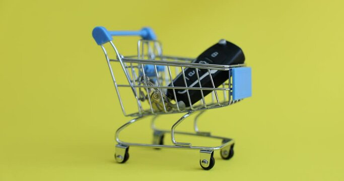 Closeup of black car key inside basket on yellow background. Leasing credit rent or purchase of car
