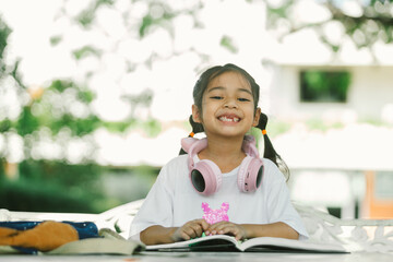 Happy asian girl reading book in the garden. Education concept.