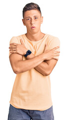 Young handsome man wearing casual clothes shaking and freezing for winter cold with sad and shock...