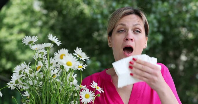 Woman with handkerchief and pollen allergy near flowers. Hay fever or seasonal allergic rhinoconjunctivitis