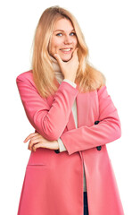 Young beautiful blonde woman wearing elegant clothes looking confident at the camera smiling with crossed arms and hand raised on chin. thinking positive.