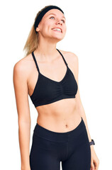 Fototapeta premium Young beautiful blonde woman wearing sportswear looking away to side with smile on face, natural expression. laughing confident.