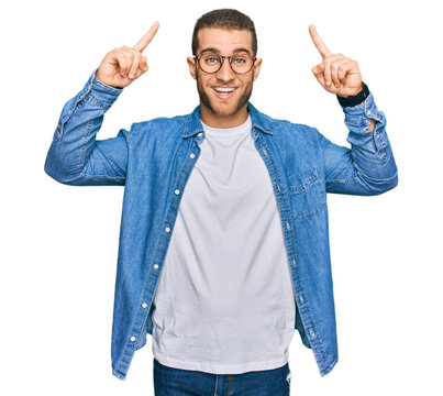 Young caucasian man wearing casual clothes smiling amazed and surprised and pointing up with fingers and raised arms.