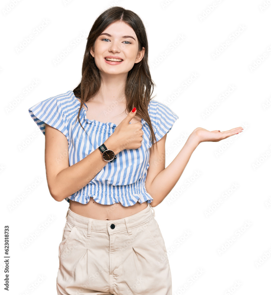 Wall mural Young beautiful caucasian girl wearing casual clothes showing palm hand and doing ok gesture with thumbs up, smiling happy and cheerful