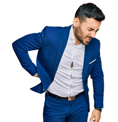 Young hispanic man wearing business jacket suffering of backache, touching back with hand, muscular pain