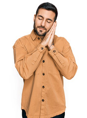 Young hispanic man wearing casual clothes sleeping tired dreaming and posing with hands together while smiling with closed eyes.