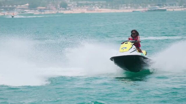 Young swarthy woman in life jacket on jet ski on the high seas