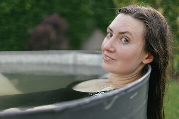 Woman relaxing in an outdoor bath tube in the backyard in summertime