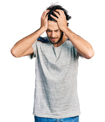 Naklejka premium Young hispanic man wearing casual t shirt suffering from headache desperate and stressed because pain and migraine. hands on head.