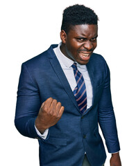 Handsome business black man wearing business suit and tie angry and mad raising fist frustrated and furious while shouting with anger. rage and aggressive concept.