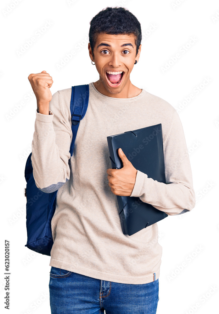 Wall mural Young african amercian man wearing student backpack holding binder screaming proud, celebrating victory and success very excited with raised arms