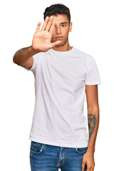 Fototapeta premium Young handsome african american man wearing casual white tshirt doing stop sing with palm of the hand. warning expression with negative and serious gesture on the face.
