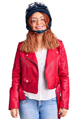 Young latin woman wearing leather jacket holding motorcycle helmet looking positive and happy standing and smiling with a confident smile showing teeth