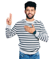 Young arab man with beard wearing casual striped sweater smiling swearing with hand on chest and...