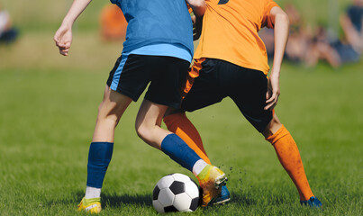 Anonymous Soccer Players Compete in a Duel on Sunny Day. Football Game For Children. Soccer Background of Young Players Kicking Classic Soccer Ball