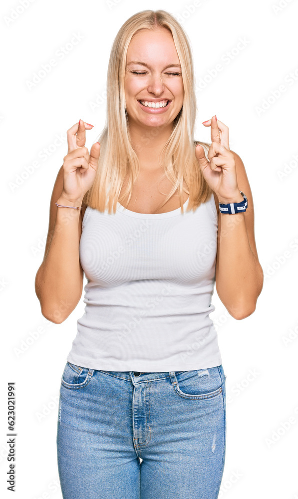 Canvas Prints Young blonde girl wearing casual style with sleeveless shirt gesturing finger crossed smiling with hope and eyes closed. luck and superstitious concept.