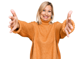 Middle age caucasian woman wearing casual winter sweater looking at the camera smiling with open arms for hug. cheerful expression embracing happiness.