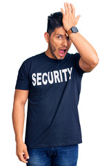 Fototapeta premium Handsome latin american young man wearing security t shirt surprised with hand on head for mistake, remember error. forgot, bad memory concept.