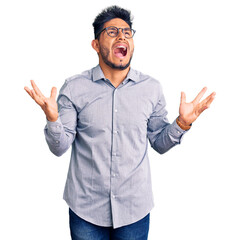 Handsome latin american young man wearing business clothes and glasses crazy and mad shouting and yelling with aggressive expression and arms raised. frustration concept. - obrazy, fototapety, plakaty