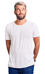 Fototapeta premium Young handsome blond man wearing casual t-shirt smiling looking to the side and staring away thinking.