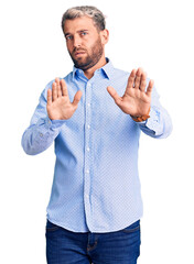 Young handsome blond man wearing elegant shirt moving away hands palms showing refusal and denial...