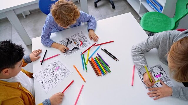 Group of school children draw picture for augmented reality. Kids in classroom use pencils prepare drawing for qr code digital tablet