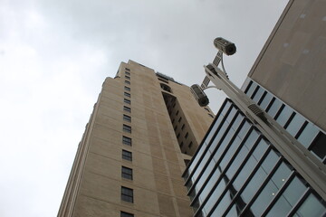 A upward angle photo of a street lamppost and a large high-rise building against a grey cloudy sky in Philadelphia, USA. 