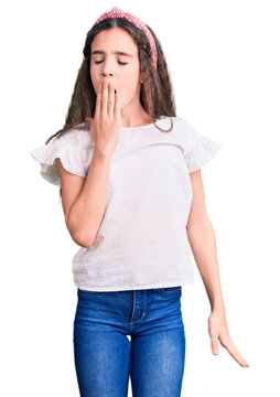 Cute hispanic child girl wearing casual white tshirt bored yawning tired covering mouth with hand. restless and sleepiness.