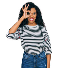 Middle age african american woman wearing casual clothes doing ok gesture with hand smiling, eye looking through fingers with happy face.