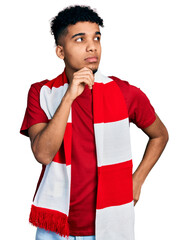 Young african american man football hooligan cheering game serious face thinking about question...