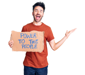 Young hispanic man holding power to the people banner celebrating victory with happy smile and winner expression with raised hands