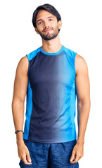 Fototapeta premium Handsome hispanic man wearing sportswear relaxed with serious expression on face. simple and natural looking at the camera.