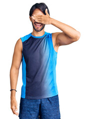 Handsome hispanic man wearing sportswear smiling and laughing with hand on face covering eyes for surprise. blind concept.