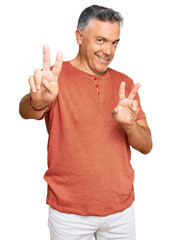 Naklejka premium Handsome middle age man wearing casual clothes smiling looking to the camera showing fingers doing victory sign. number two.
