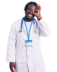 Young african american man with braids wearing doctor stethoscope and id pass smiling happy doing ok sign with hand on eye looking through fingers