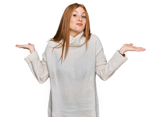 Young irish woman wearing casual winter sweater clueless and confused expression with arms and...