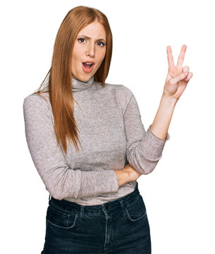 Young irish woman wearing casual clothes smiling with happy face winking at the camera doing victory sign. number two.