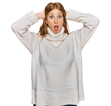 Young irish woman wearing casual winter sweater crazy and scared with hands on head, afraid and surprised of shock with open mouth