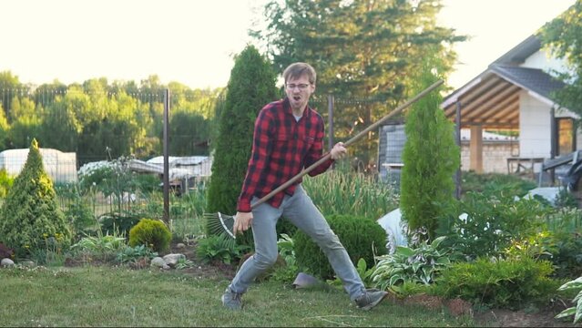 Gardener or farmer man holding rake like a guitar. Working in garden. Funny farm life concept.