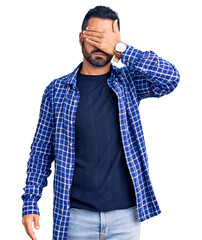 Young hispanic man wearing casual clothes covering eyes with hand, looking serious and sad. sightless, hiding and rejection concept